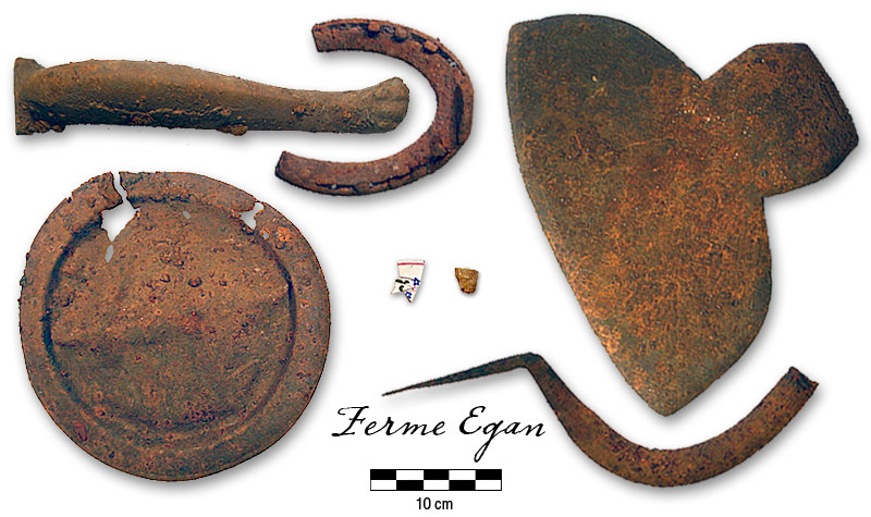 Photographie : fourneau de pipe &agrave; effigie, tasse &agrave; th&eacute; en c&eacute;ramique, , pied de po&ecirc;le, fer &agrave; cheval cass&eacute; et clous, faucille unie, hache &agrave; &eacute;quarrir