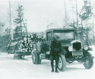 Photograph of truck pulling sleighload of logs